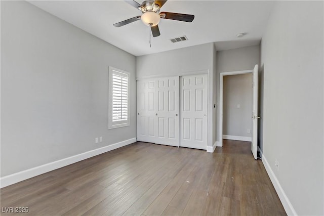 unfurnished bedroom with visible vents, baseboards, a ceiling fan, wood finished floors, and a closet