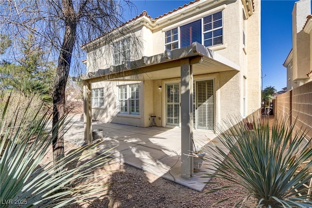 back of property with a tiled roof, fence, a patio, and stucco siding