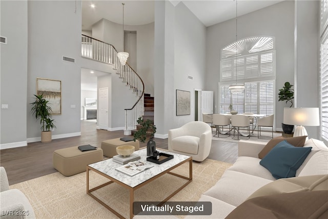 living room with visible vents, stairway, baseboards, and wood finished floors