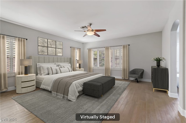 bedroom featuring a ceiling fan, baseboards, visible vents, and wood finished floors