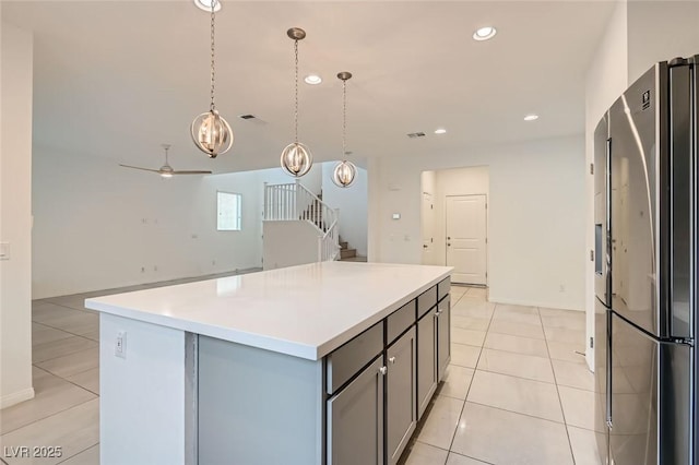 kitchen featuring recessed lighting, light countertops, gray cabinetry, freestanding refrigerator, and a kitchen island