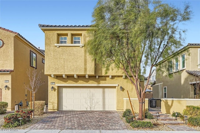 mediterranean / spanish house with decorative driveway, an attached garage, and stucco siding