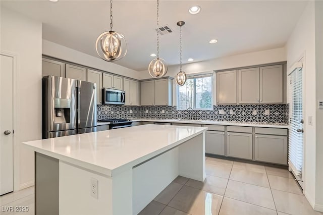 kitchen featuring stainless steel appliances, a center island, visible vents, and gray cabinetry