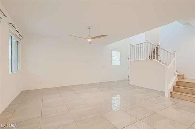 spare room with light tile patterned floors, stairway, and a ceiling fan