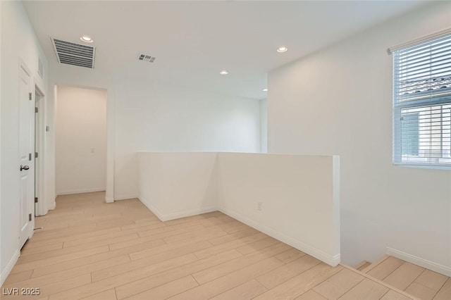 spare room with light wood finished floors, baseboards, visible vents, and recessed lighting