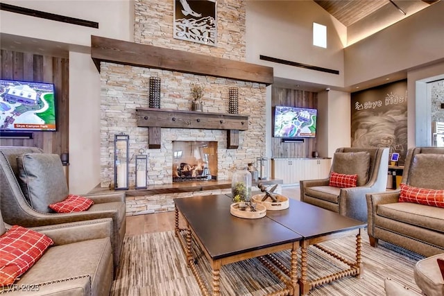 living room with a stone fireplace, a high ceiling, and wood finished floors