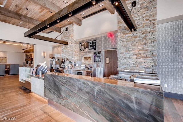 kitchen with a towering ceiling, beam ceiling, and wood finished floors