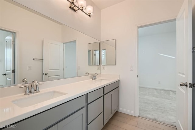 bathroom featuring double vanity, a sink, and baseboards