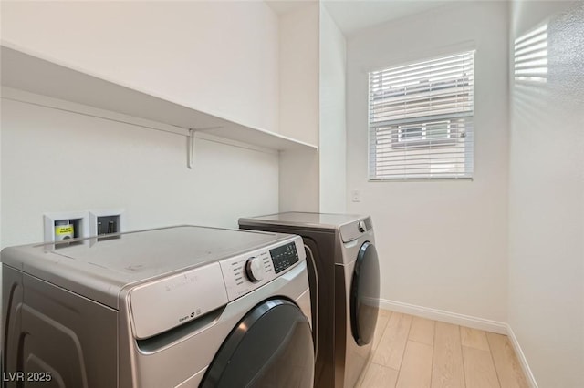 laundry area with laundry area, baseboards, washer and clothes dryer, and light wood-style floors