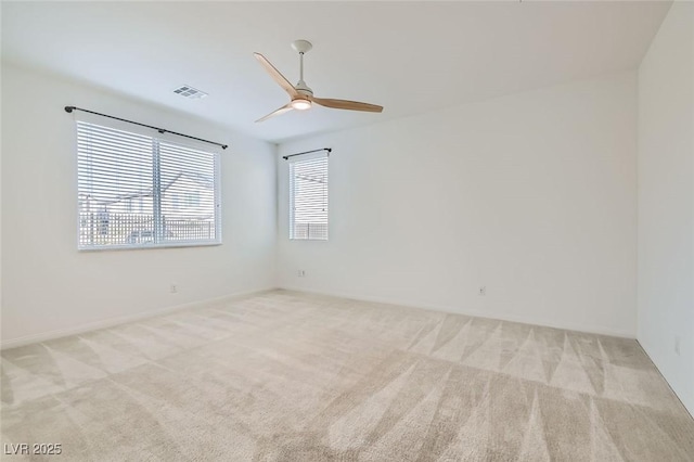 spare room with carpet, visible vents, and a ceiling fan