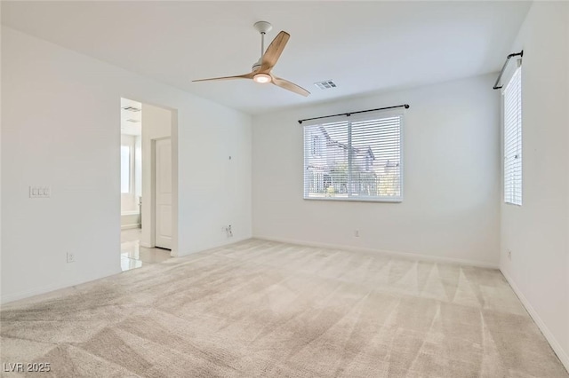 empty room featuring baseboards, a ceiling fan, visible vents, and light colored carpet