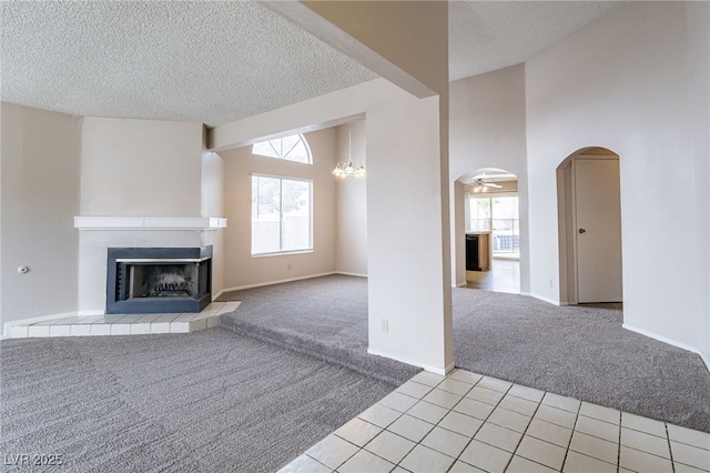 unfurnished living room featuring light carpet, plenty of natural light, a fireplace, and arched walkways