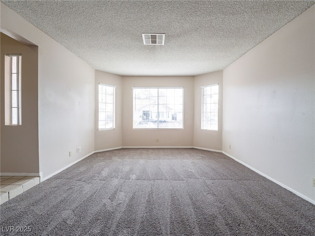 carpeted spare room featuring a textured ceiling, visible vents, and baseboards