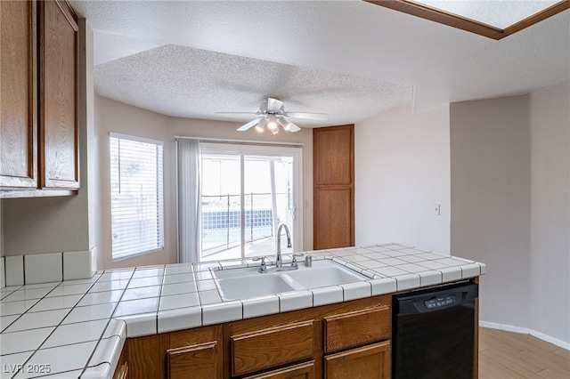 kitchen with black dishwasher, a sink, a ceiling fan, and brown cabinets