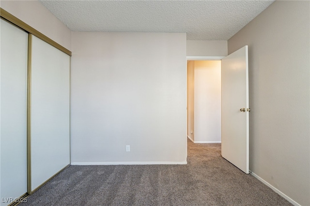 unfurnished bedroom with a textured ceiling, a closet, carpet, and baseboards