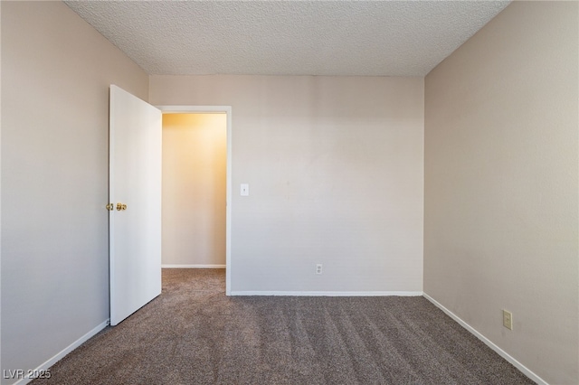 spare room with carpet, baseboards, and a textured ceiling