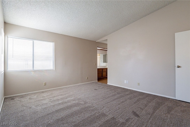 carpeted empty room featuring a textured ceiling and baseboards