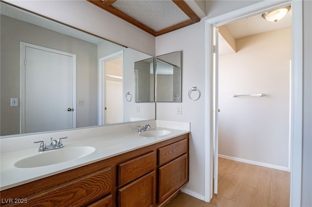 bathroom featuring double vanity, wood finished floors, a sink, and baseboards