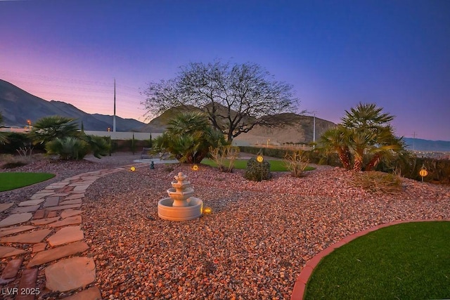 yard at dusk with a mountain view and fence