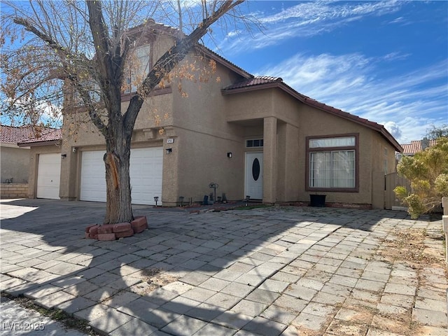 mediterranean / spanish-style house featuring driveway, an attached garage, a tile roof, and stucco siding