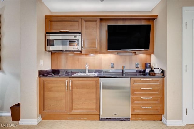 bar with a sink, baseboards, appliances with stainless steel finishes, wet bar, and light floors