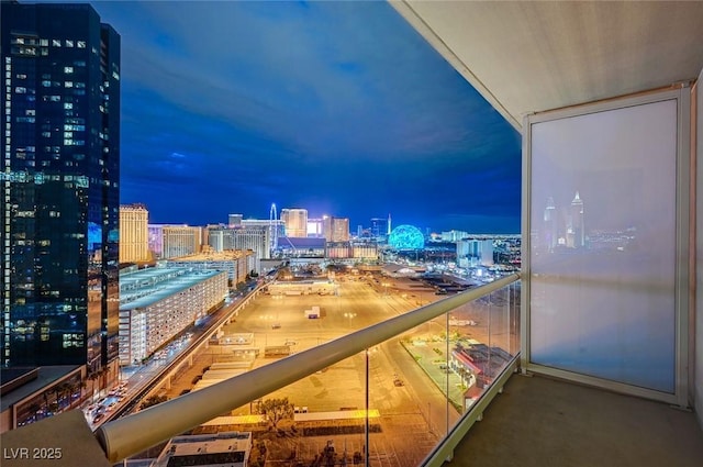 balcony at night featuring a view of city lights