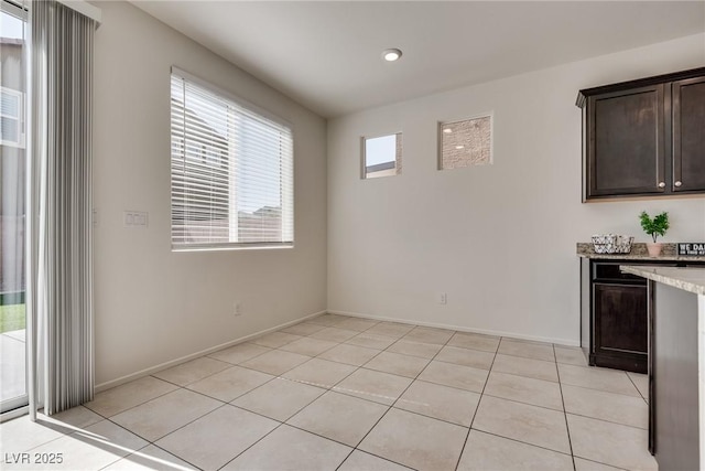 unfurnished dining area featuring light tile patterned floors and baseboards