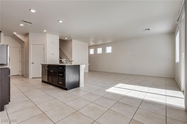 kitchen with light tile patterned floors, freestanding refrigerator, open floor plan, and visible vents