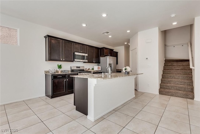 kitchen featuring appliances with stainless steel finishes, visible vents, an island with sink, and light tile patterned floors