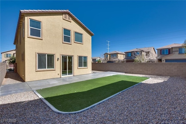 back of house with a yard, a fenced backyard, a patio, and stucco siding