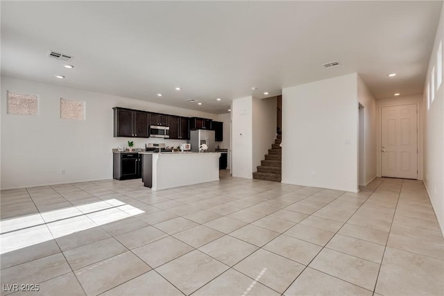 unfurnished living room featuring stairway, light tile patterned flooring, and visible vents