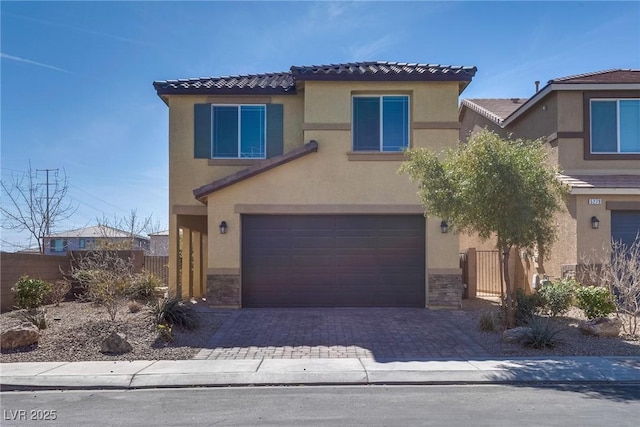 view of front facade featuring stone siding, fence, an attached garage, and stucco siding