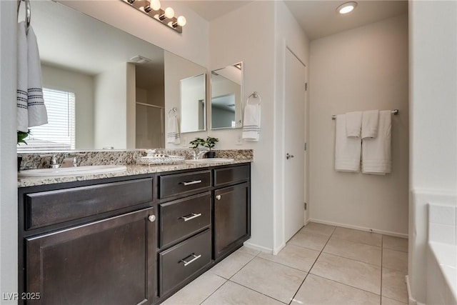 bathroom featuring double vanity, tile patterned flooring, a sink, and baseboards