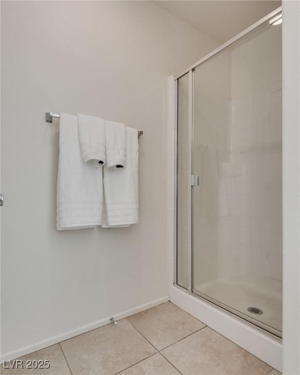 bathroom with a shower stall, baseboards, and tile patterned floors