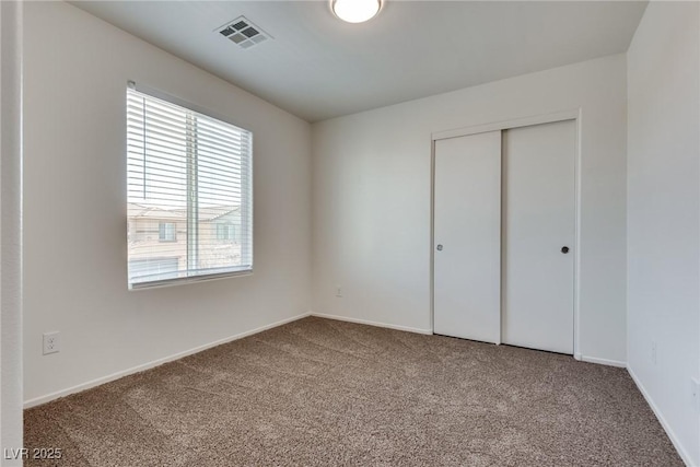 unfurnished bedroom with baseboards, carpet, visible vents, and a closet