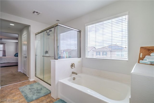 ensuite bathroom featuring connected bathroom, a garden tub, a healthy amount of sunlight, and a stall shower