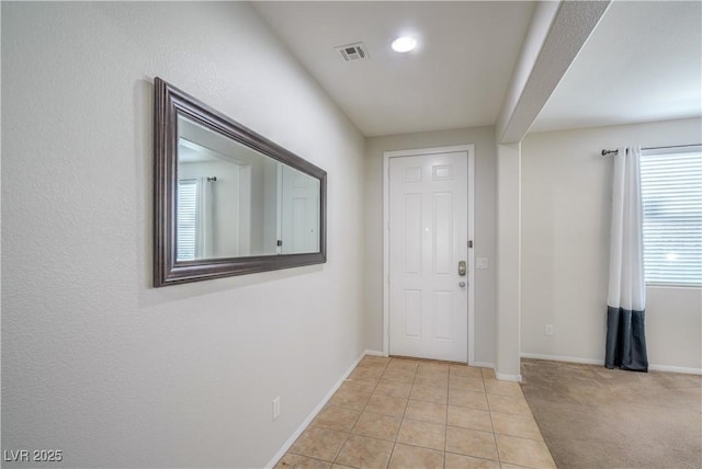 entrance foyer featuring light tile patterned floors, visible vents, light carpet, and baseboards