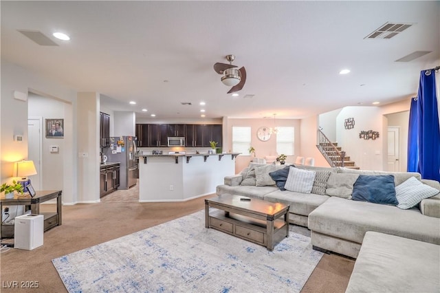 living area with recessed lighting, visible vents, light colored carpet, and stairs