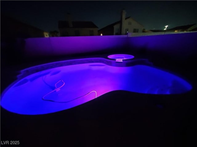 pool at night featuring a fenced backyard