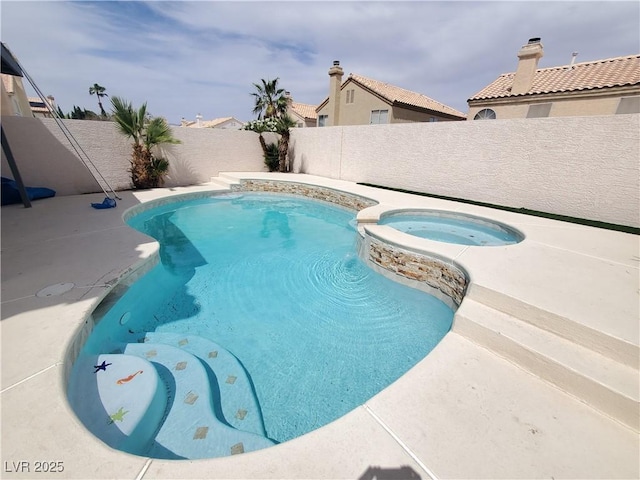 view of pool with a fenced backyard and a pool with connected hot tub