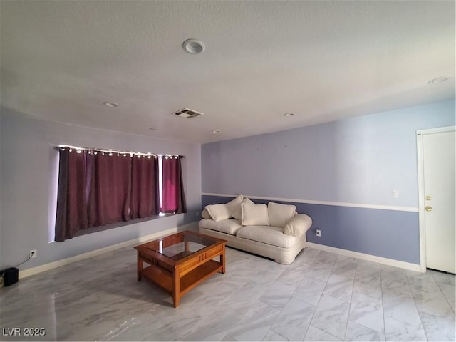 living area featuring marble finish floor, visible vents, a textured ceiling, and baseboards