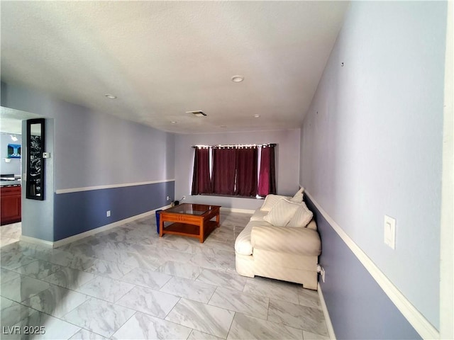 sitting room with a textured ceiling, marble finish floor, visible vents, and baseboards