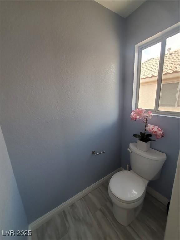 bathroom with toilet, baseboards, and wood finished floors