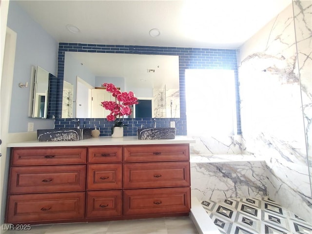 full bath featuring double vanity, tasteful backsplash, and a sink