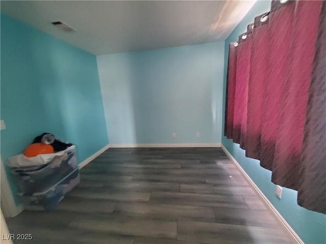 empty room with wood finished floors, visible vents, and baseboards