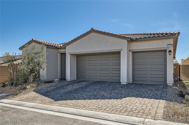 exterior space with stucco siding, decorative driveway, a garage, and a tile roof