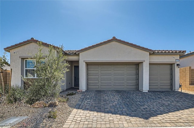 view of front of property with stucco siding, a tile roof, decorative driveway, and a garage