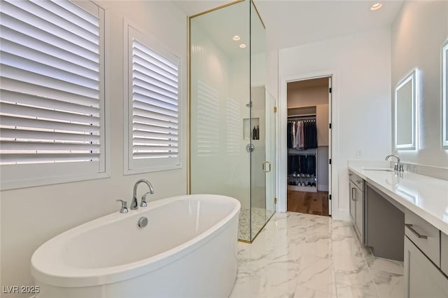 bathroom featuring a spacious closet, a shower stall, a freestanding tub, marble finish floor, and vanity