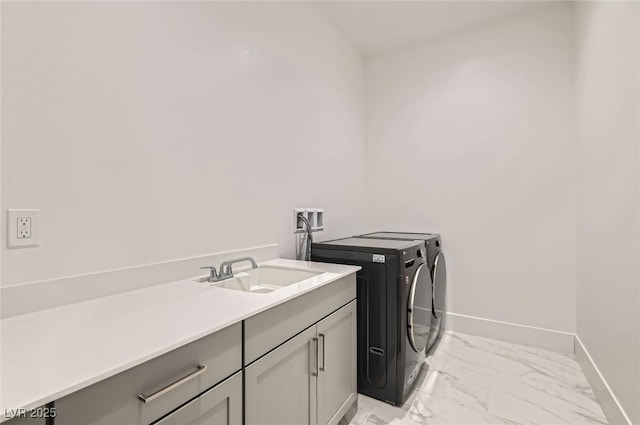 washroom with marble finish floor, a sink, washing machine and dryer, cabinet space, and baseboards