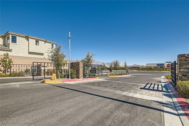 view of street with curbs, traffic signs, a gate, a gated entry, and street lights